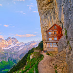 Mountain lodge built into rock face offers stunning views of Swiss Alps and lake at sunset