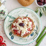 Dakos traditional Greek appetizer on a traditional plate with ceramic olive oil jar, dry rye bread, olives and olive branch. Healthy eating concept. Mediterranean lifestyle.