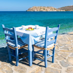 Crete Greece Plaka Lassithi, a traditional blue table and chairs on the beach in Crete Greece. Paralia Plakas, Plaka village Crete.