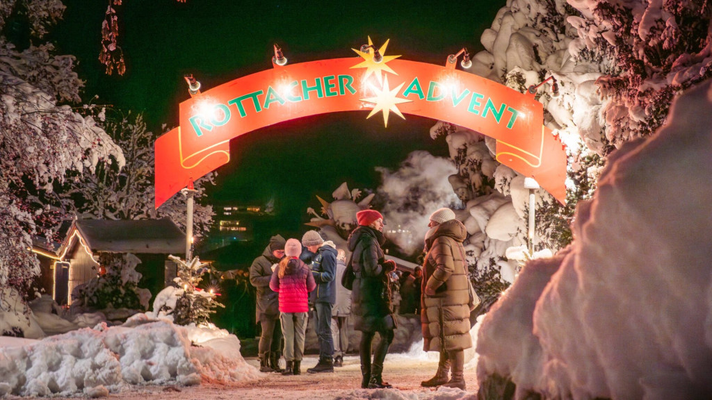 Stimmungsvoll beleuchtet und umgeben von verschneiten Bäumen, genießen Besucher den Adventsmarkt in Rottach-Egern.